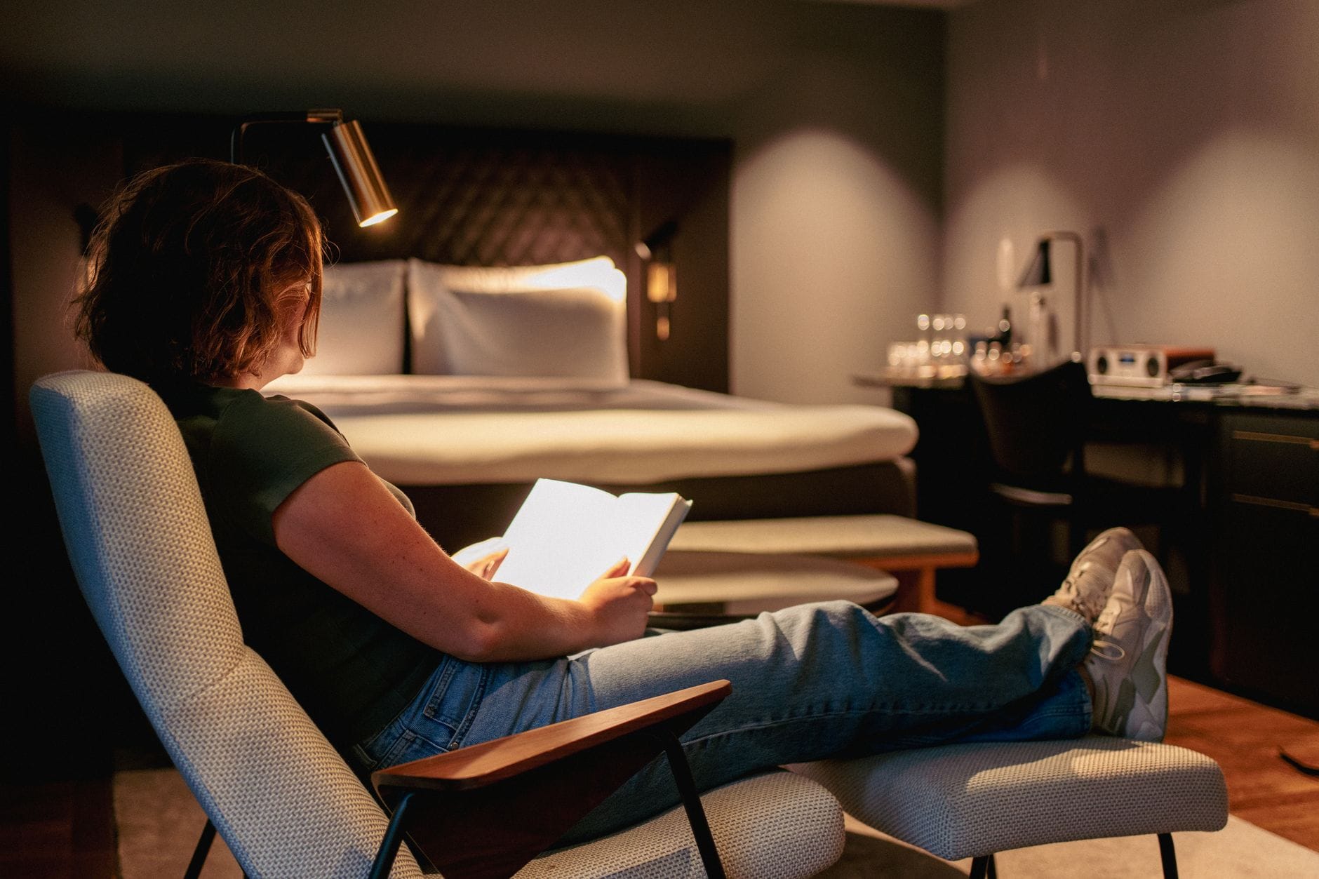 Woman relaxing and reading in a modern Stockholm hotel room, creating cozy ambiance.